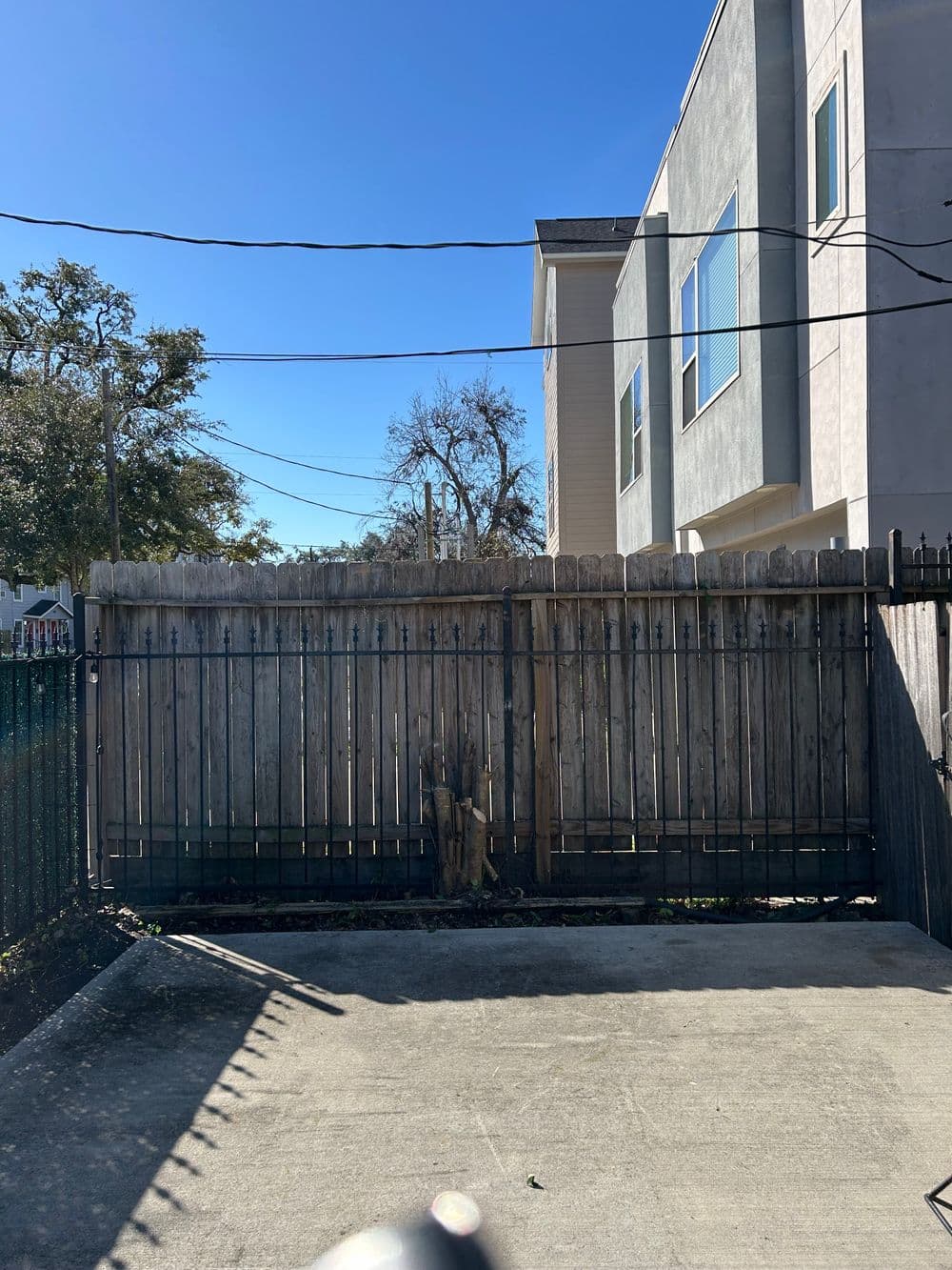 Fenced outdoor area with concrete pavement and a clear blue sky in the background.