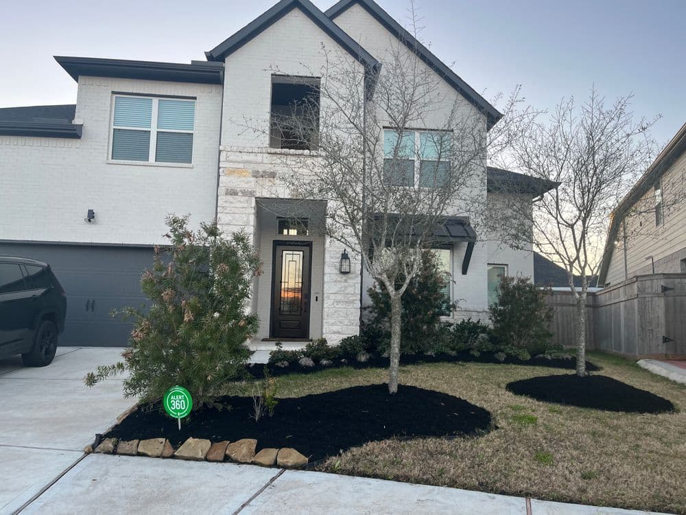 Modern two-story home with landscaped yard, trees, and driveway at sunset.