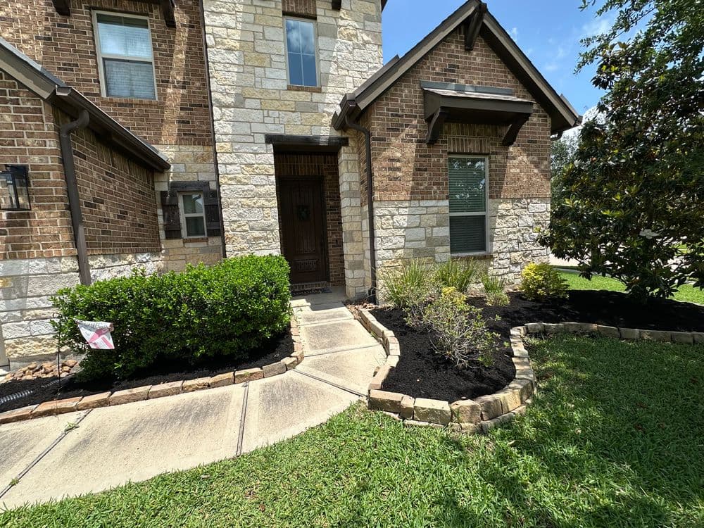 Entrance pathway of a modern brick home with landscaped garden and stone accents.